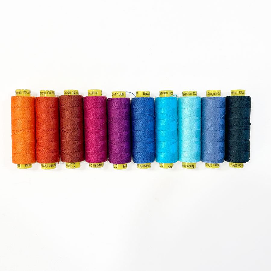 A collection of spools of hand quilting thread in a variety of colors arranged in a line.