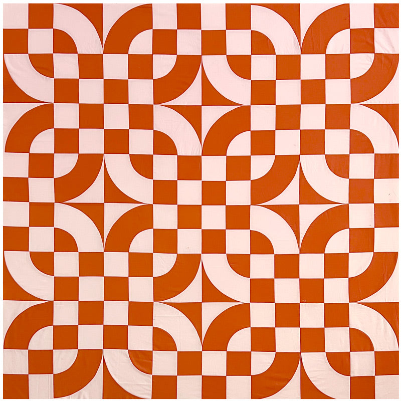 A quilt made of curves and checkerboards in peach and pumpkin colors.