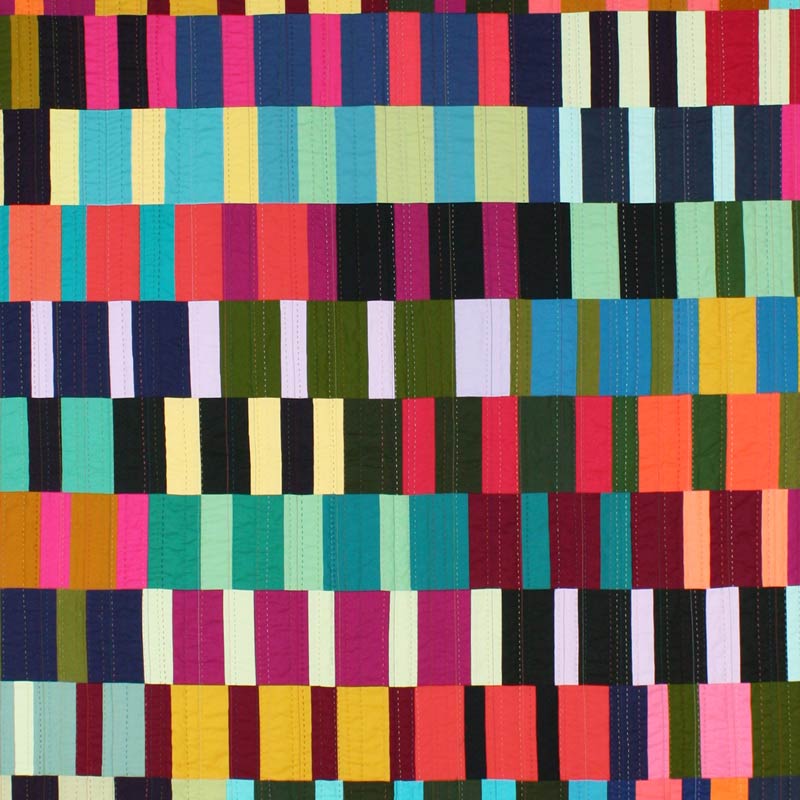 close up of colorful quilt made of rectangles- shows hand quilting