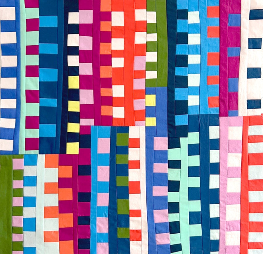 A colorful quilt with a zipper pattern, featuring a variety of bright colors and geometric shapes.
