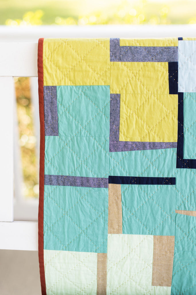 Picture of the give and take quilt draped over the side of a chair on a porch