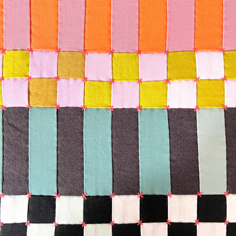 Close-up of handmade art with colorful stitches and geometric forms, perfect for brightening home decor.