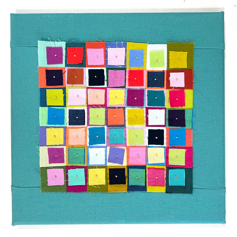 Small quilted wall art with raw edge squares in bright colors on a teal background. Squares are stitched with a french knot.