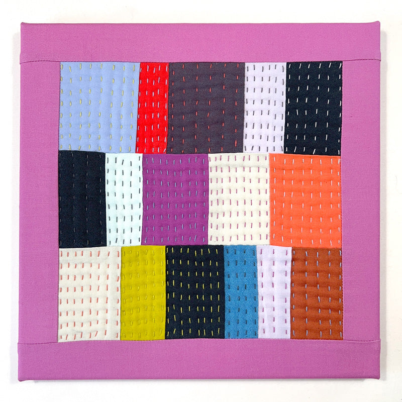 Small quilted wall art composed of rectangles, heavily hand quilted with a variety of bright colors.