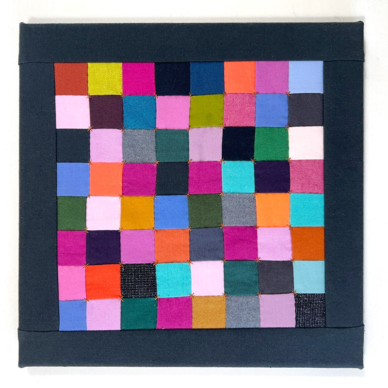 Small quilted wall art composed of gem toned squares, hand quilted with a small bronze X in the corners.