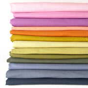 Stack of colorful fabric swatches in various shades on a white background
