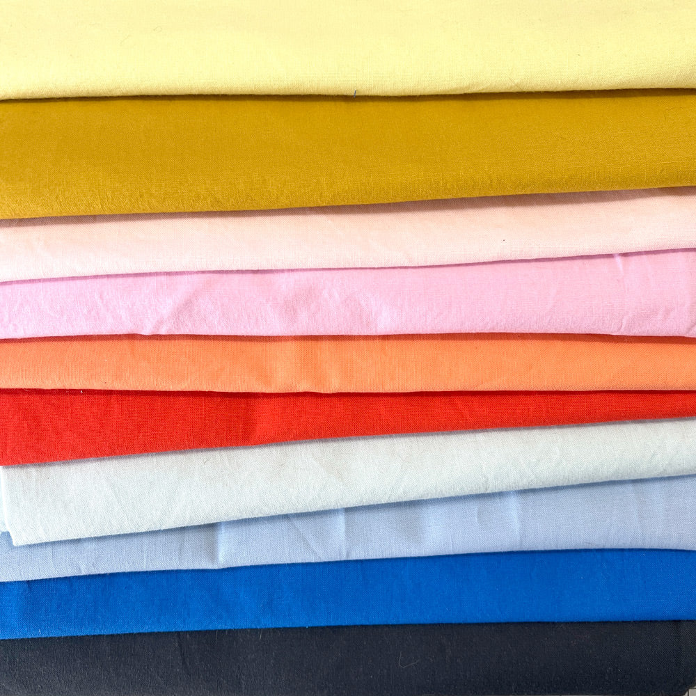 A pile of rainbow colored quilting fabrics