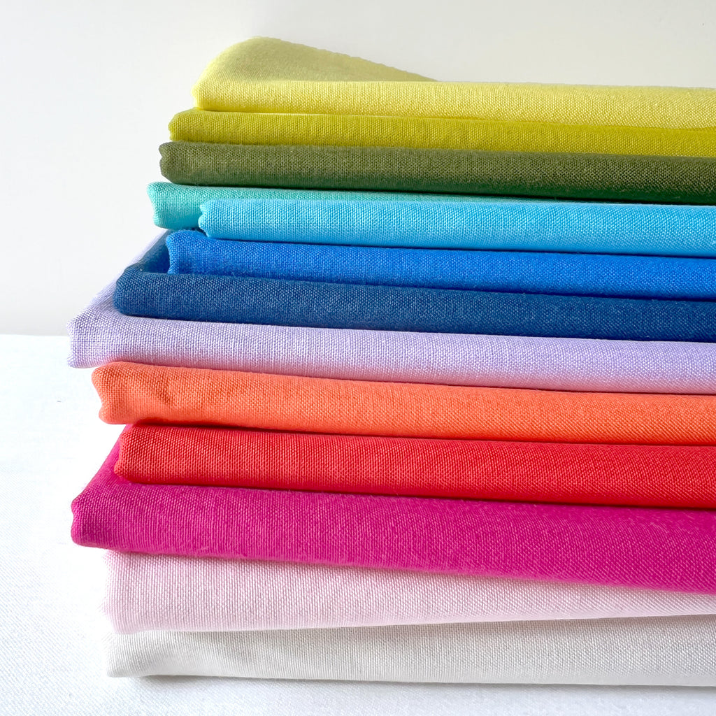 A colorful pile of fabrics in a rainbow of colors.