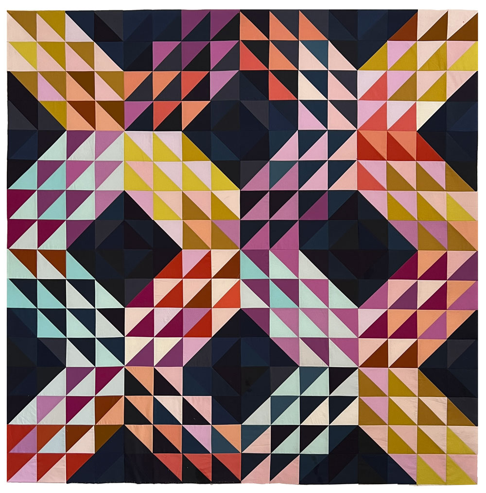 A throw quilt made of half square triangles in an "x" pattern. Made of rainbow colors and a dark navy background.
