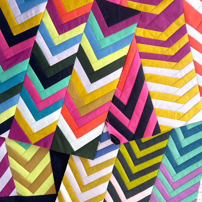 A pile of small colorful quilt studies in a chevron pattern.