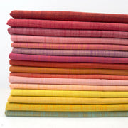 Stack of colorful fabric swatches in various shades of pink, orange, yellow, and red on a white background.