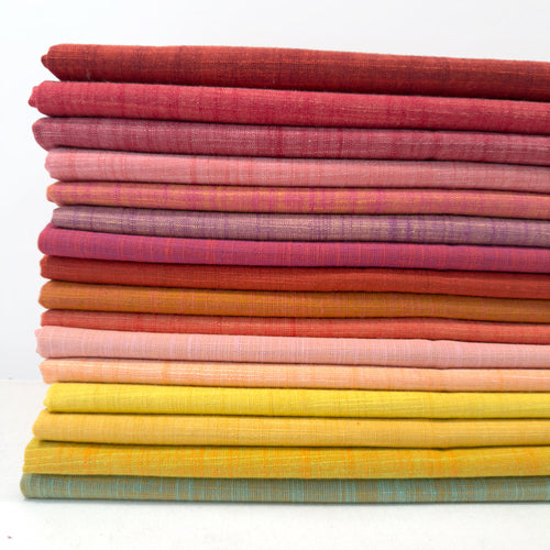 Stack of colorful fabric swatches in various shades of pink, orange, yellow, and red on a white background.