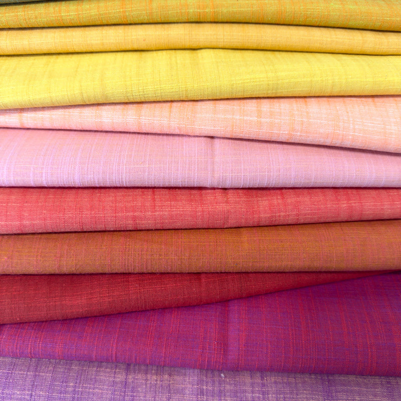 Stack of colorful fabric swatches in various shades.