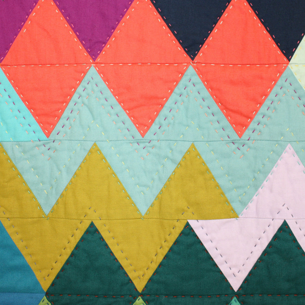 Small quilt block in bright colors, made up of rows of triangles