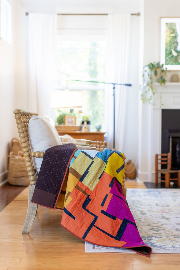 Picture of the give and take quilt draped over the side of a chair in a living room
