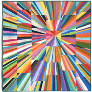 A square quilt with a vivid radial geometric pattern made of many brightly colored striped and block sections radiating from the center, shown flat against a plain white background.