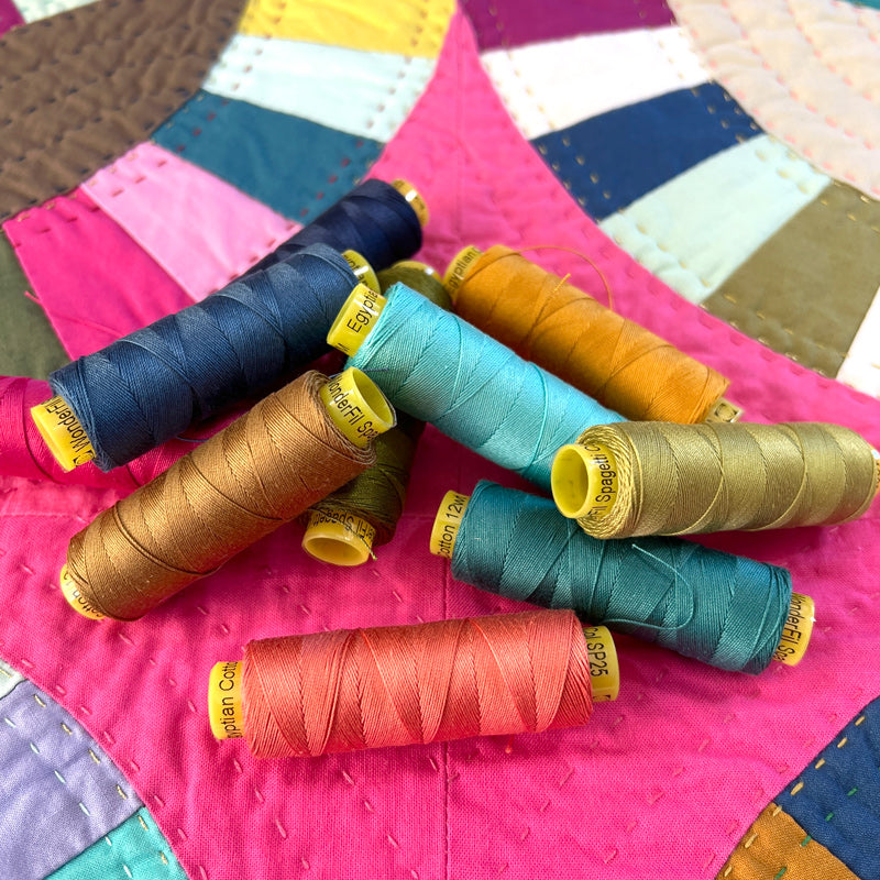 Spools of colorful thread on a patchwork quilt