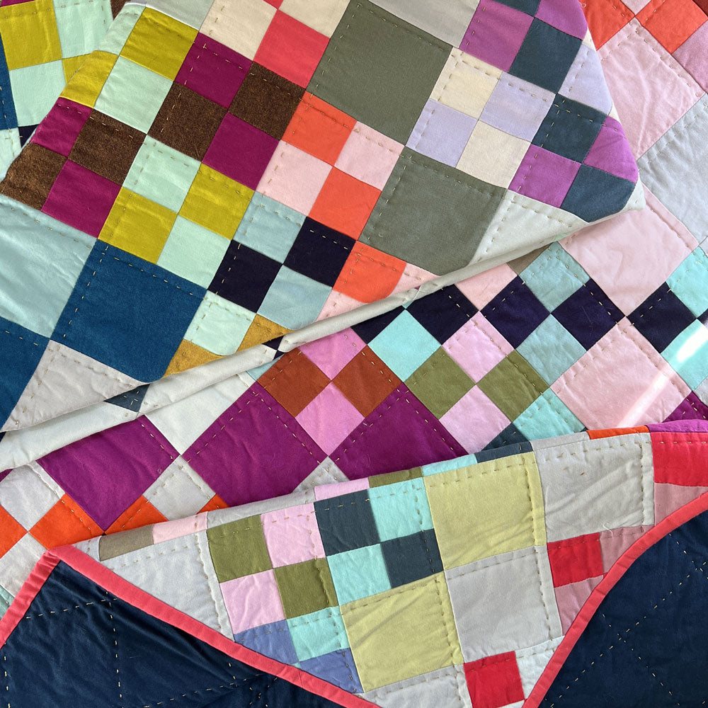 Close-up of a colorful quilt with metallic hand quilting
