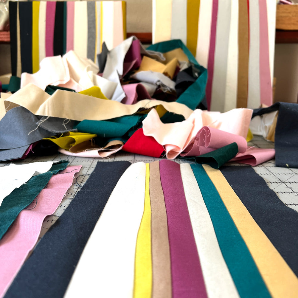 Sewn lines of various widths in pinks, grays, whites and yellows.