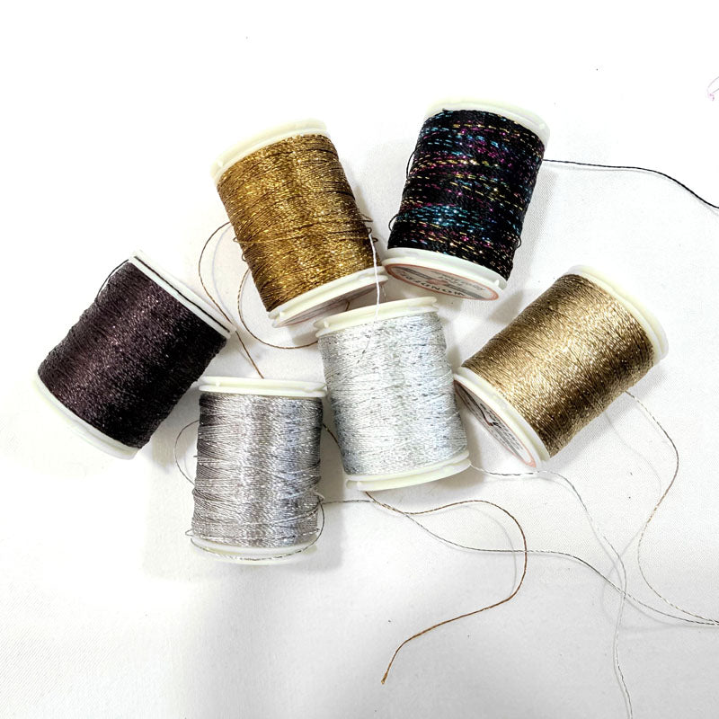 Spools of metallic thread in various colors on a white background