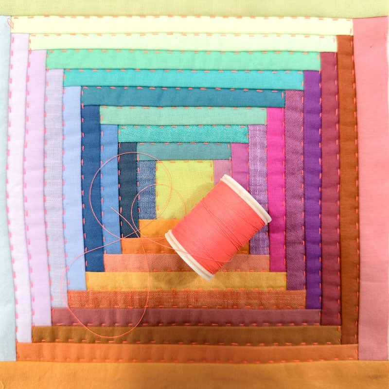 Colorful quilt with a spool of thread on it