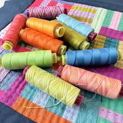Colorful spools of thread on a patchwork fabric background