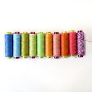Row of colorful spools of thread on a white background