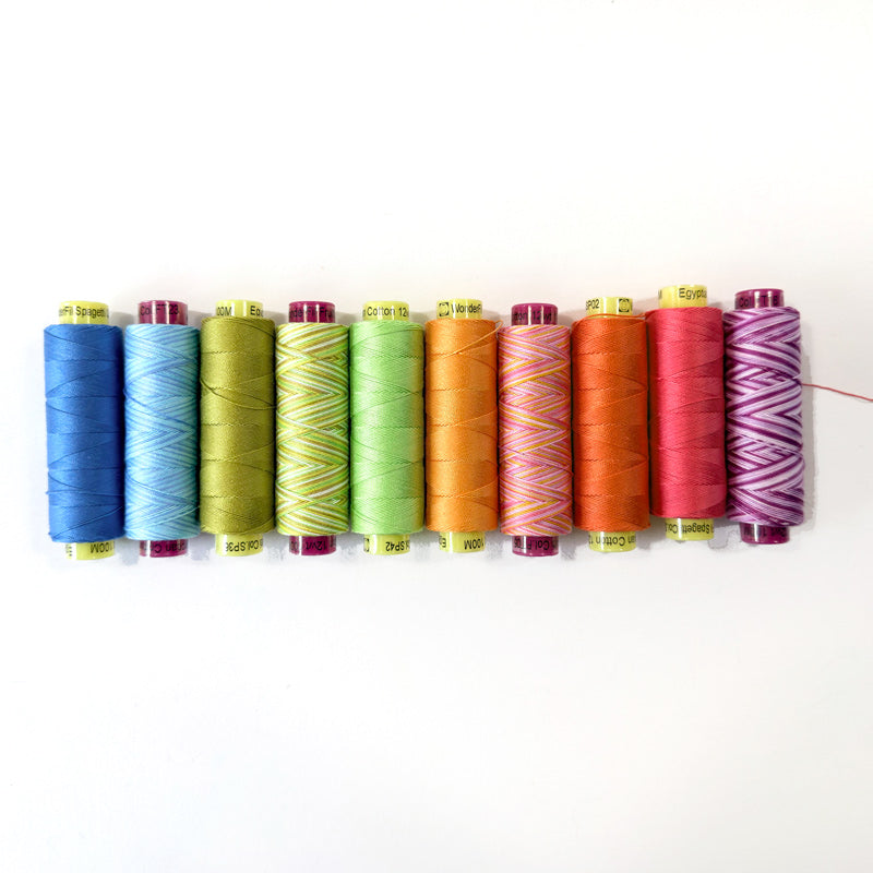 Row of colorful spools of thread on a white background