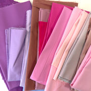 Collection of colorful fabric pieces in shades of pink and purple arranged in a row.