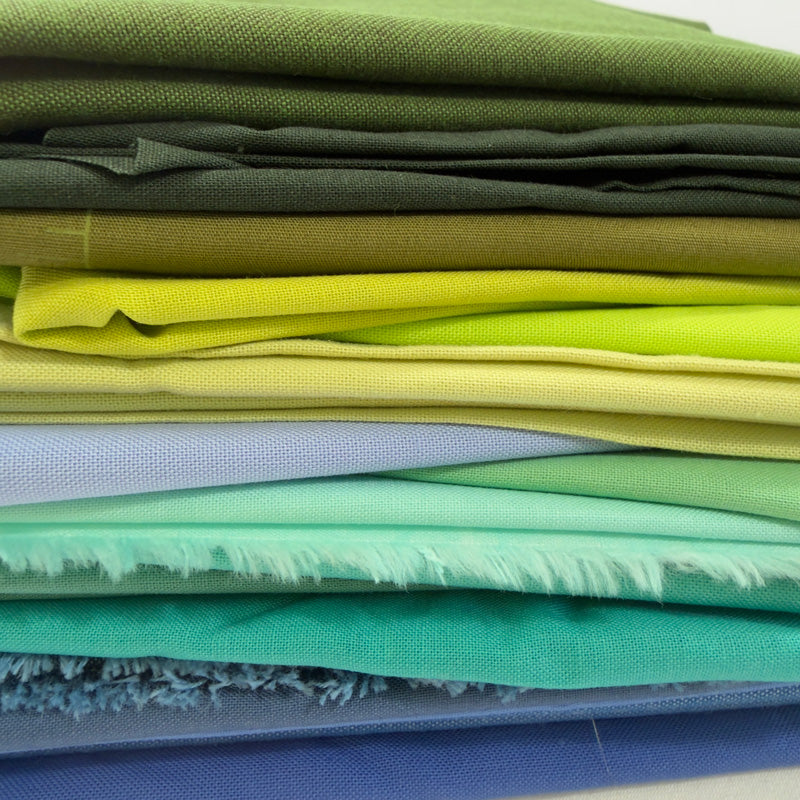 Stack of colorful fabric swatches in various shades of green, yellow, and blue.