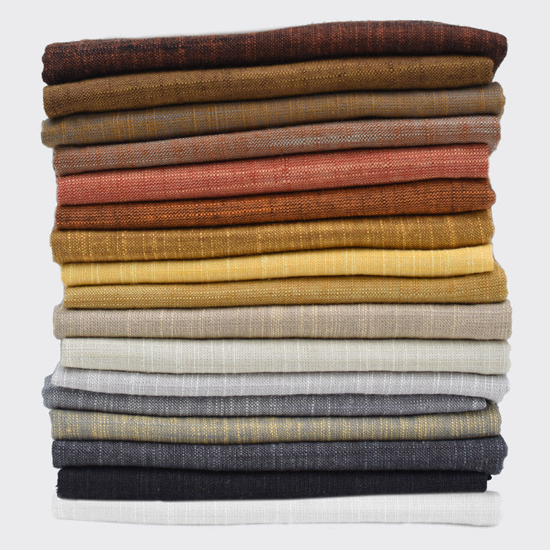 Stack of folded fabric swatches in various colors on a white background