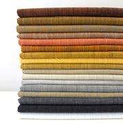 Stack of folded fabric swatches in various colors on a white background