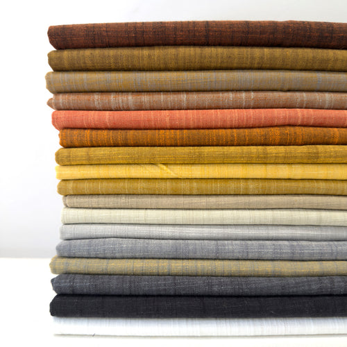 Stack of folded fabric swatches in various colors on a white background