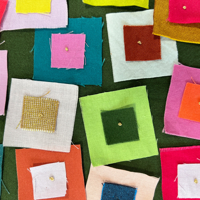 Close up of Small quilted wall art with raw edge squares in bright colors on a green background. Squares are stitched with a french knot.