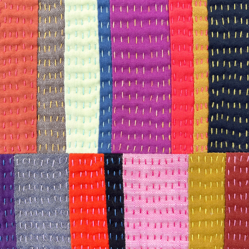 Close up of Small quilted wall art composed of rectangles, heavily hand quilted with a variety of bright colors.