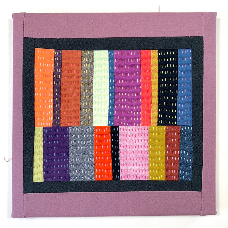 Small quilted wall art composed of rectangles, heavily hand quilted with a variety of bright colors.