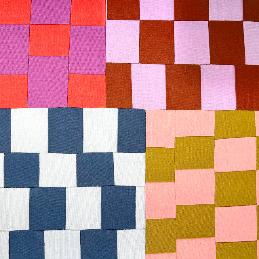 A close up of a small textile wall art made of multi color improvisational squares, stretched on a canvas.