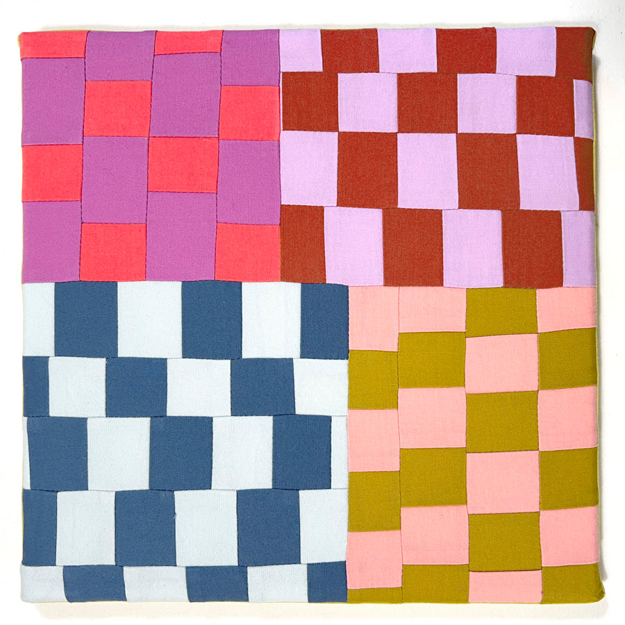 A small textile wall art made of multi color improvisational squares, stretched on a canvas.