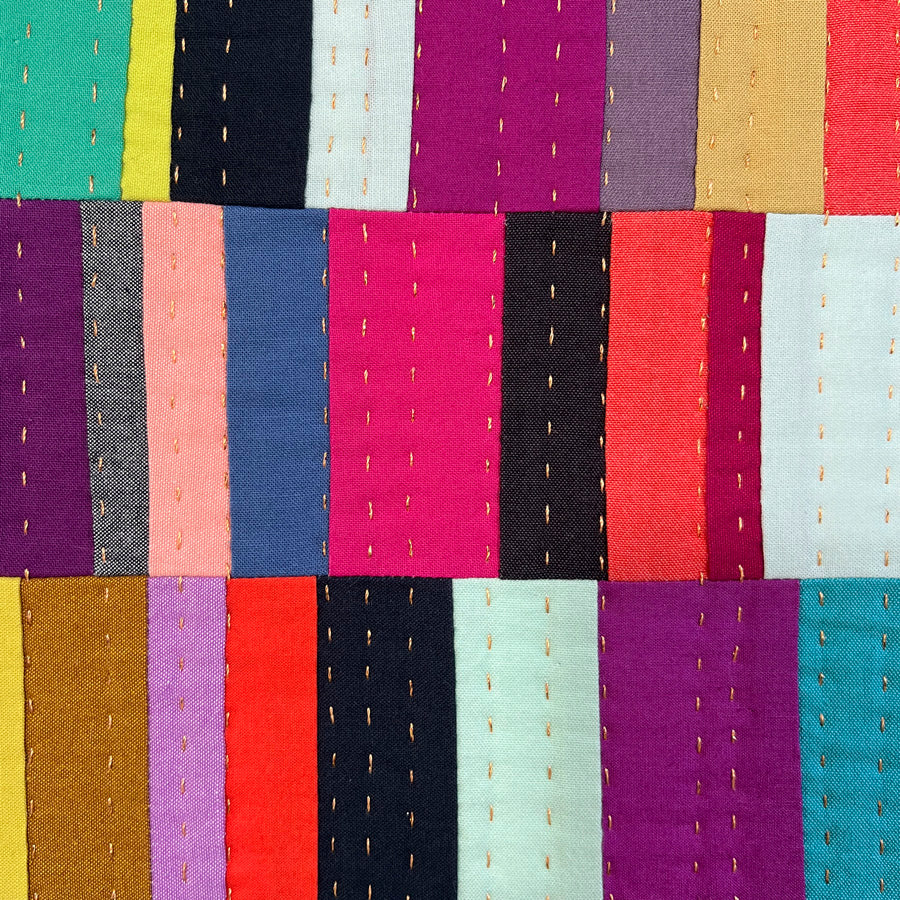  A close up of a small quilted wall art composed of multiple bright color rectangles that is hand pieced, hand quilted and stretched on archival acid free canvas.