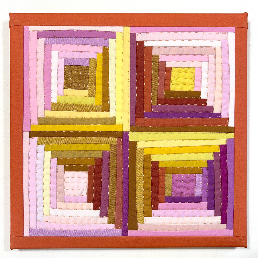 A small pieced log cabin block made of pink and yellow and brown fabrics, stretched on a canvas with metallic gold hand quilting.