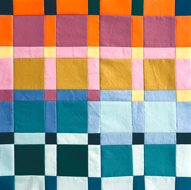 Colorful patchwork mini quilt with square patterns on a white background