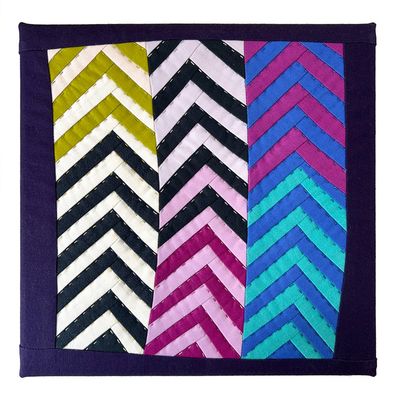 Quilt with colorful chevron patterns and hand quilting  on a white background.