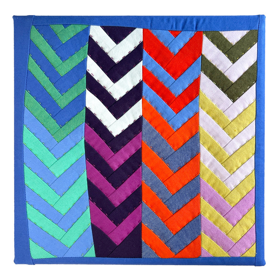 Colorful quilt with chevron pattern with hand quilting on a white background