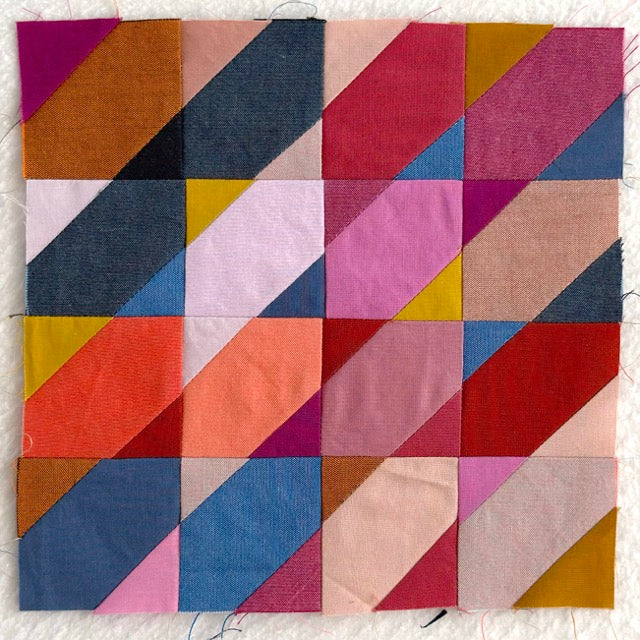 Colorful patchwork quilt block with geometric pattern on a white background