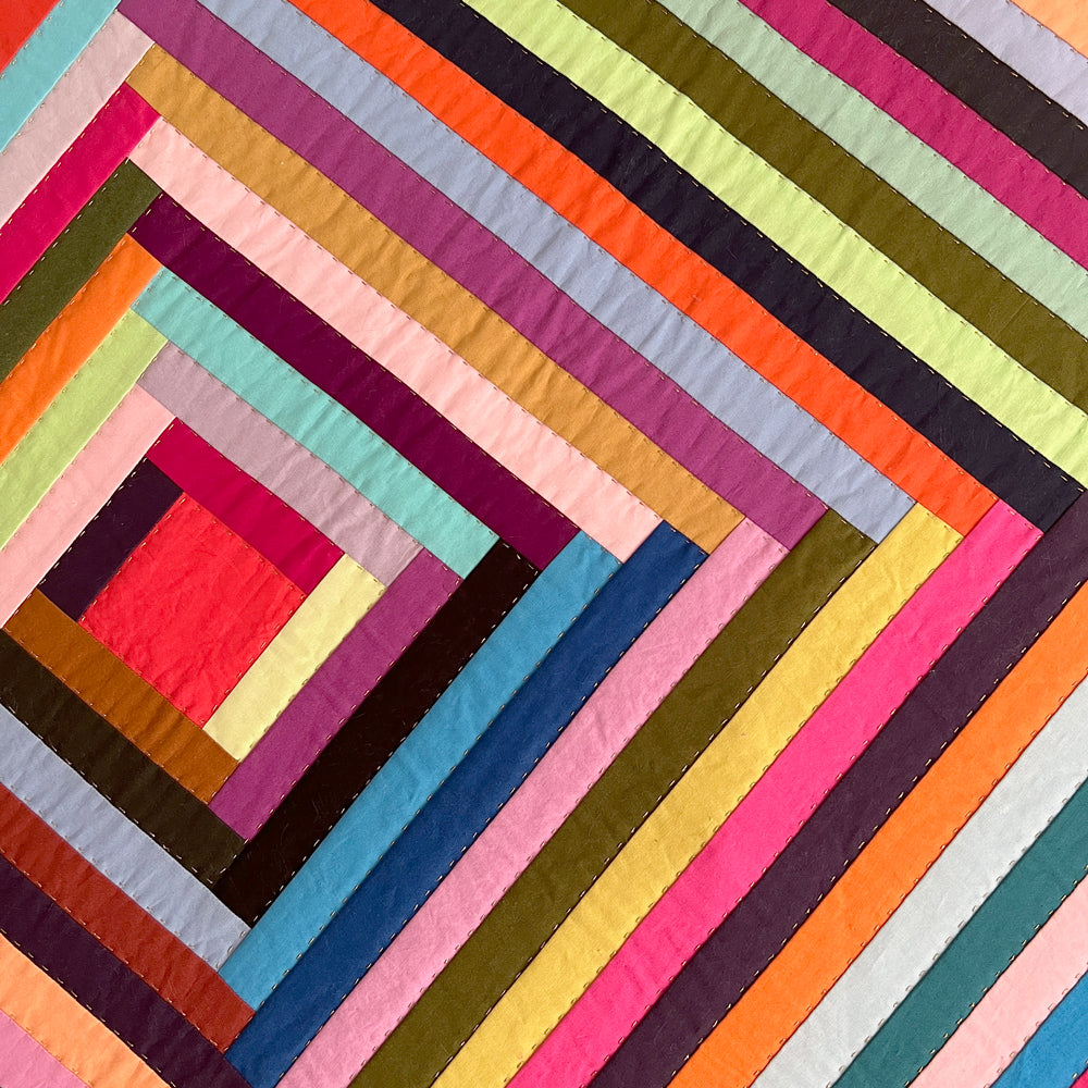 Close up of Big Log Cabin quilt in a rainbow of multiple colors.