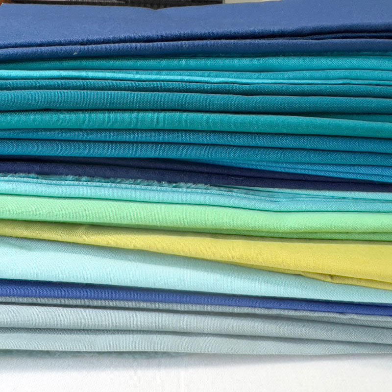 Stack of colorful fabric swatches in various shades.