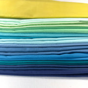 Stack of colorful fabric swatches in yellow, green, blue on a white background