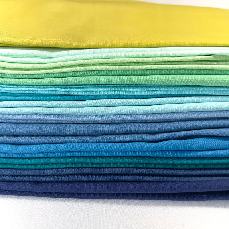 Stack of colorful fabric swatches in yellow, green, blue on a white background