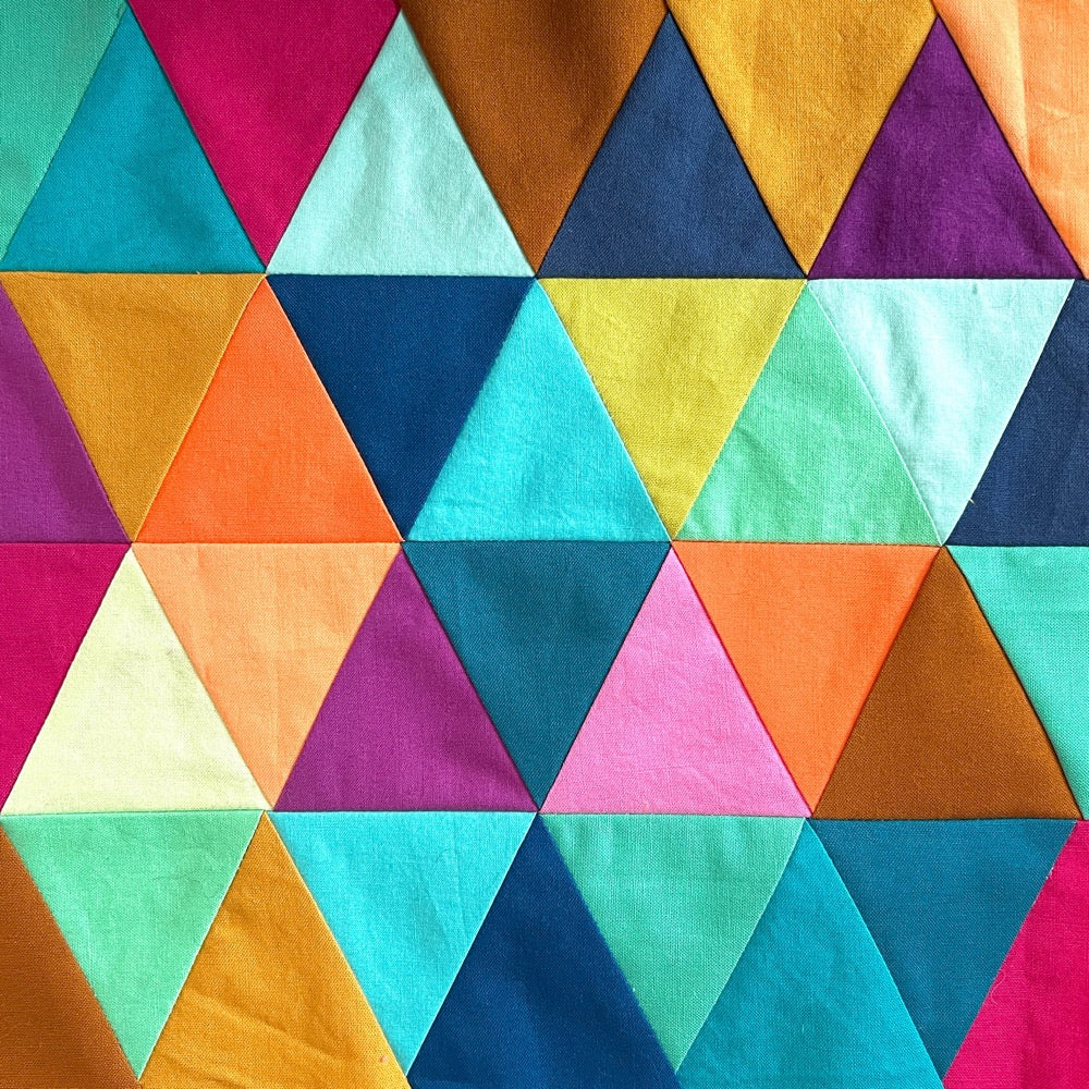 Small quilt block in bright colors, made up of rows of triangles