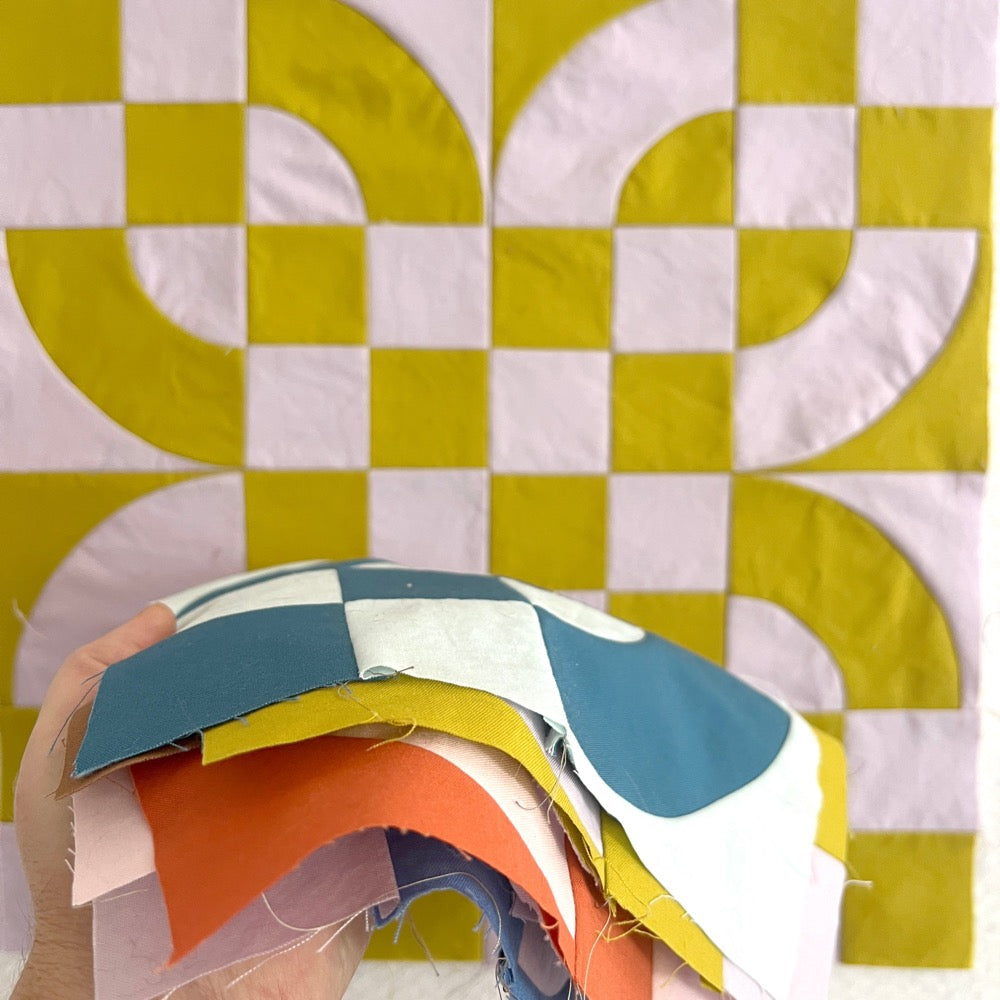 Quilt blocks in a pile, in multiple colors, made of 4 patches and drunkards path blocks